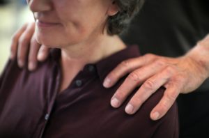 Hände legen sich auf Schultern